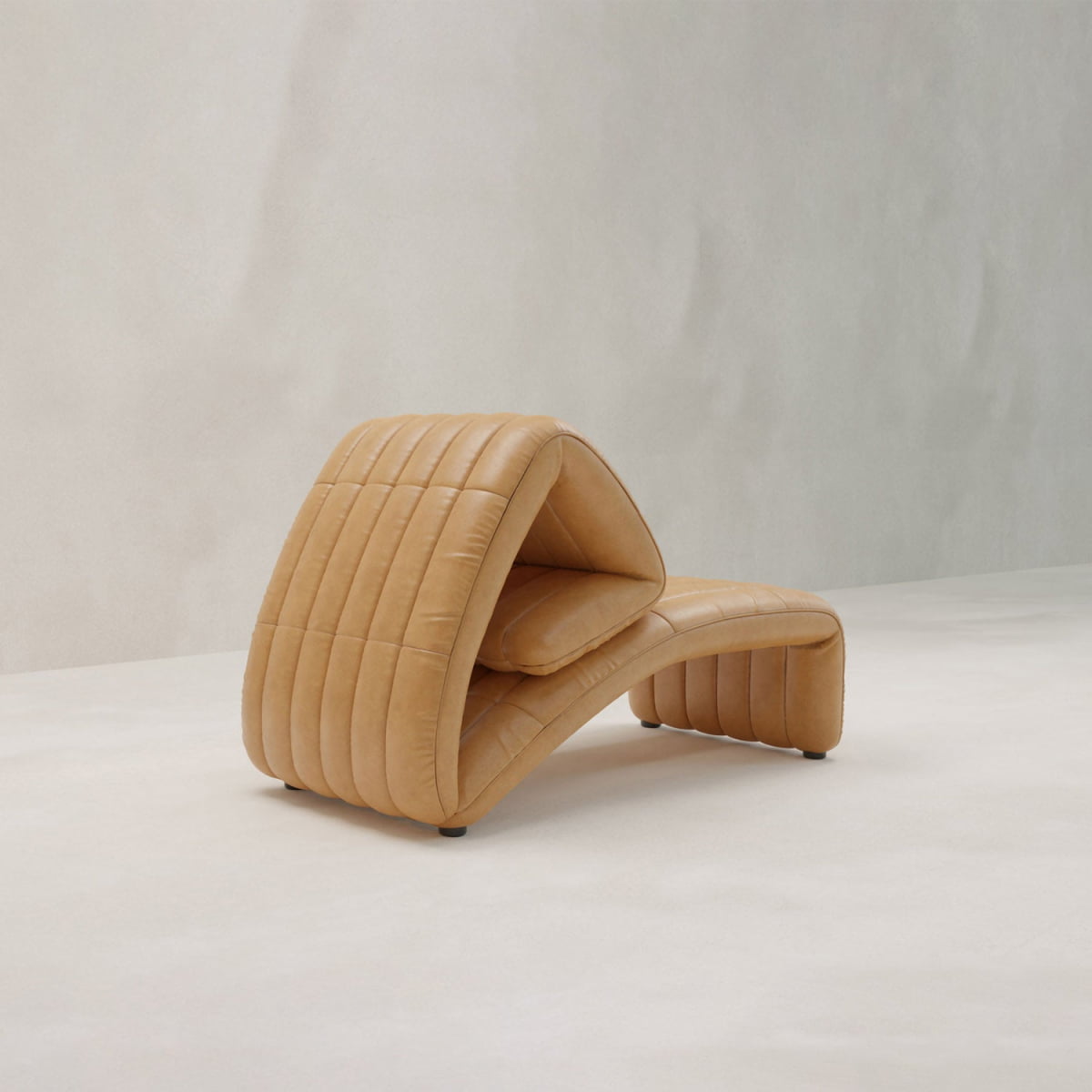 The Hillier Chair, featuring premium vintage leather, a sculptural curved form, and vertical stitching, is placed in a minimal light-colored room.