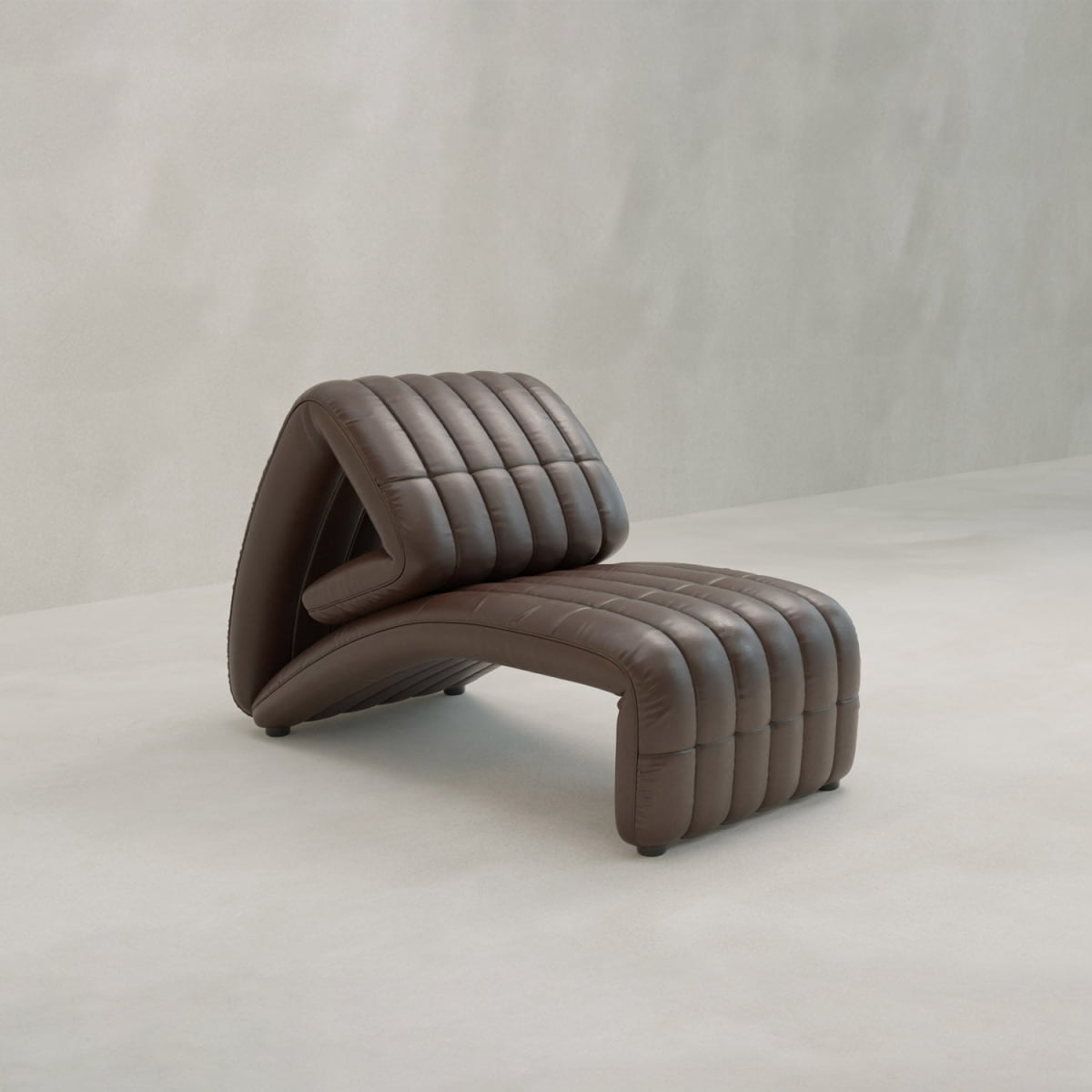 The Hillier Chair features a modern, sculptural arched design with subtle reclining, upholstered in premium vintage leather with horizontal quilting on a neutral background.