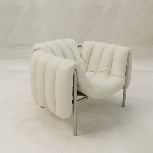 The Mallow Chair features plush cream upholstery, deep channeled tufting, and a soft quilted design on sleek metal legs, all set against a neutral, minimal background.