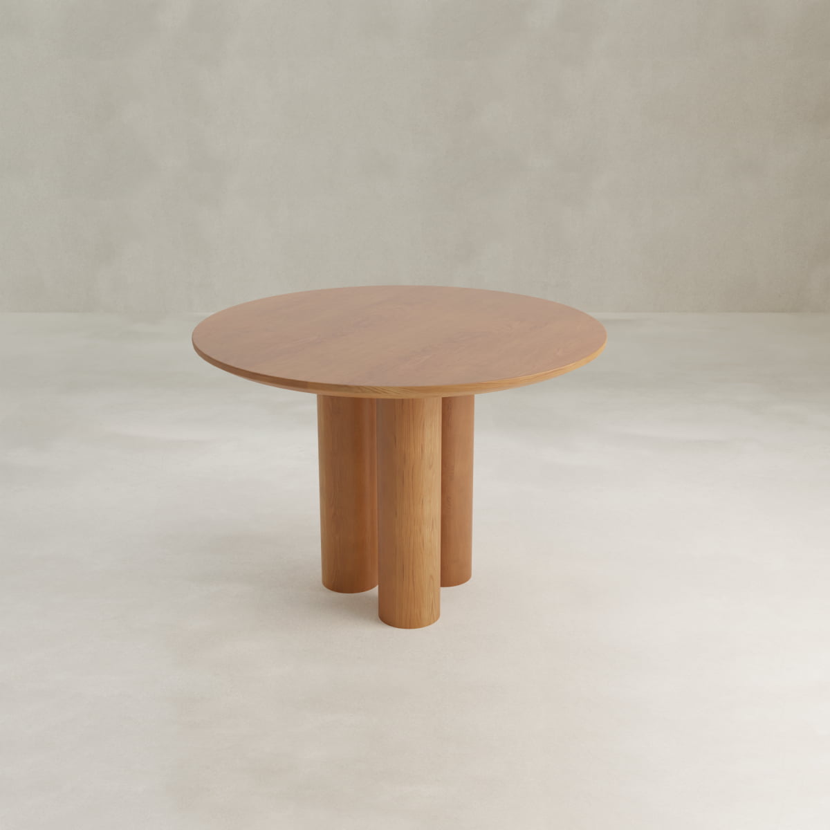 The Milo Large Wood Dining Table adds a modern feel to compact spaces with its smooth round wooden top and three sturdy cylindrical legs, displayed on a light floor with a neutral backdrop.