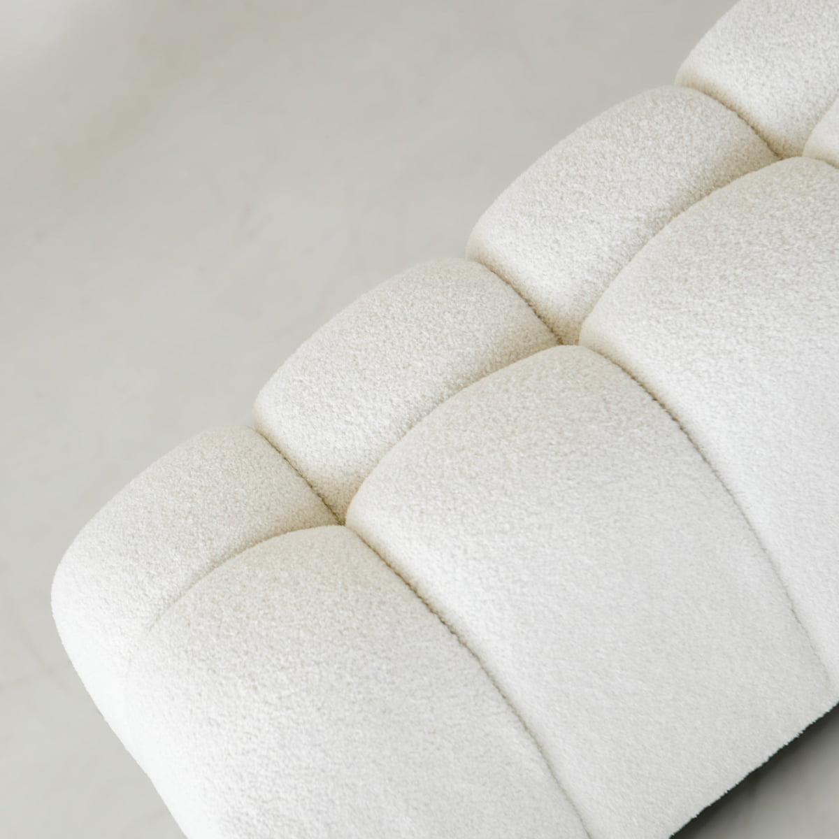 Close-up of the Olivia Bench, a white boucle bench featuring textured, rounded tufted sections in a grid pattern, set against a light-colored background.