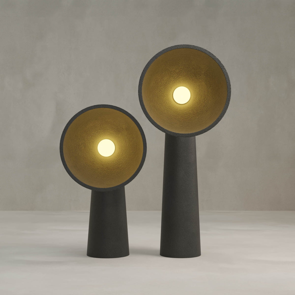 The Orbis Medium Floor Lamp features a modern black cone-shaped base and a gold-lined wide circular shade that emits warm light, all set against a plain light gray background, evoking sculptural artistry.