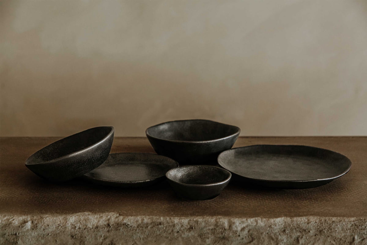 A Pebble Speckled Dish Large is arranged on a textured brown surface against a neutral beige background.