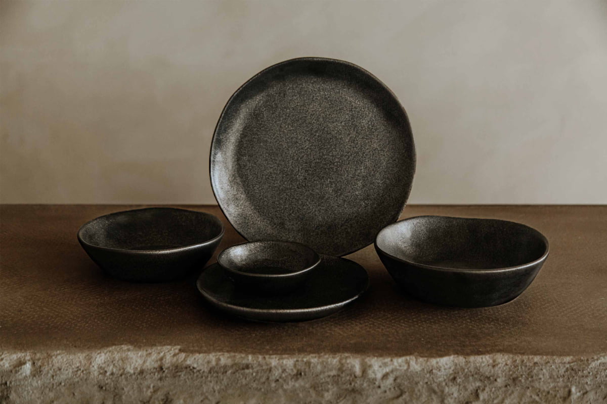 A Pebble Speckled Bowl Medium is displayed on a textured stone surface against a plain, neutral background.