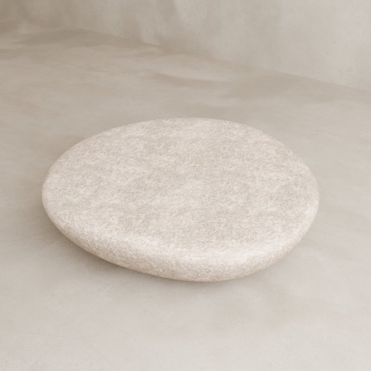 The Pluto Coffee Table features a large, round white design with a smooth light beige surface, set against a neutral floor and background to create a serene, minimalistic look that emphasizes modern style.