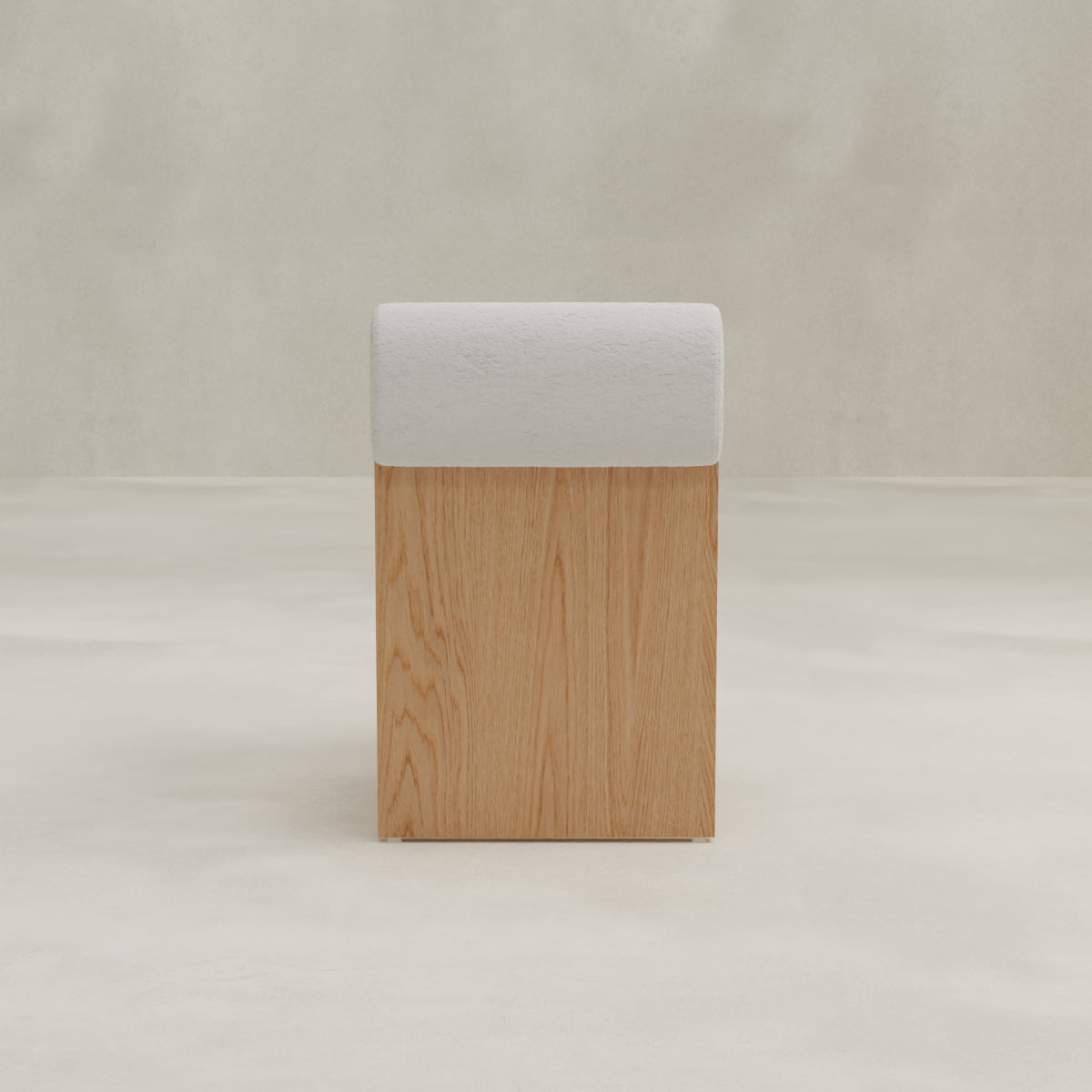 The Primrose Chair is a minimalist wooden stool featuring a rectangular base and a rounded, light gray bouclé fabric cushioned top, displayed on a light floor against a plain, neutral background.