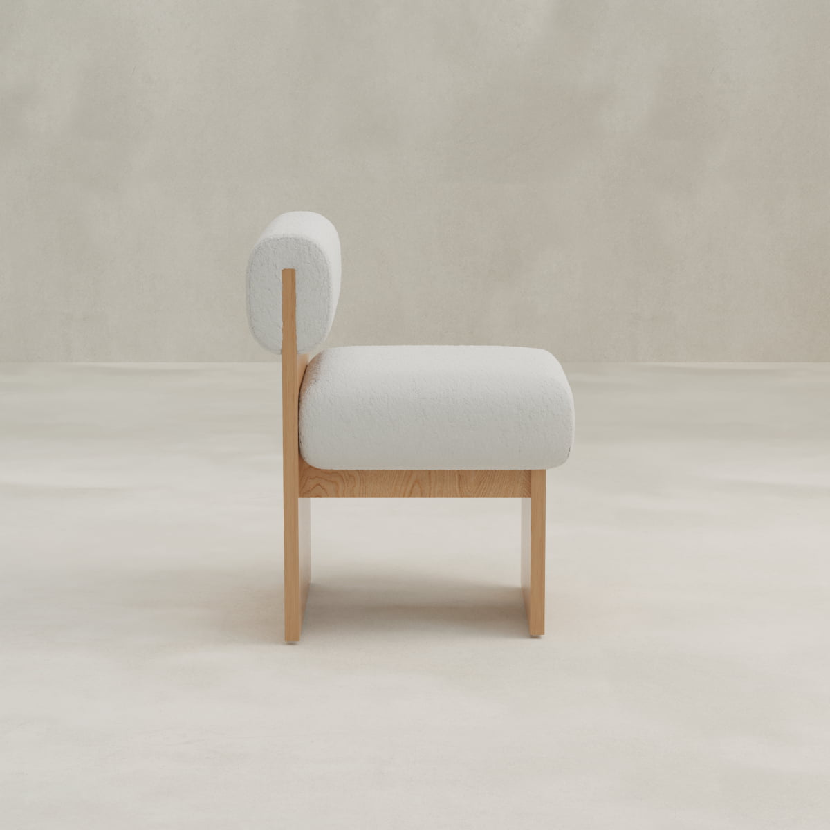 The Primrose Chair features a modern design with light wood legs and frame, complemented by a rounded white bouclé fabric cushioned seat and backrest for ergonomic support, photographed from the side against a minimalist backdrop.
