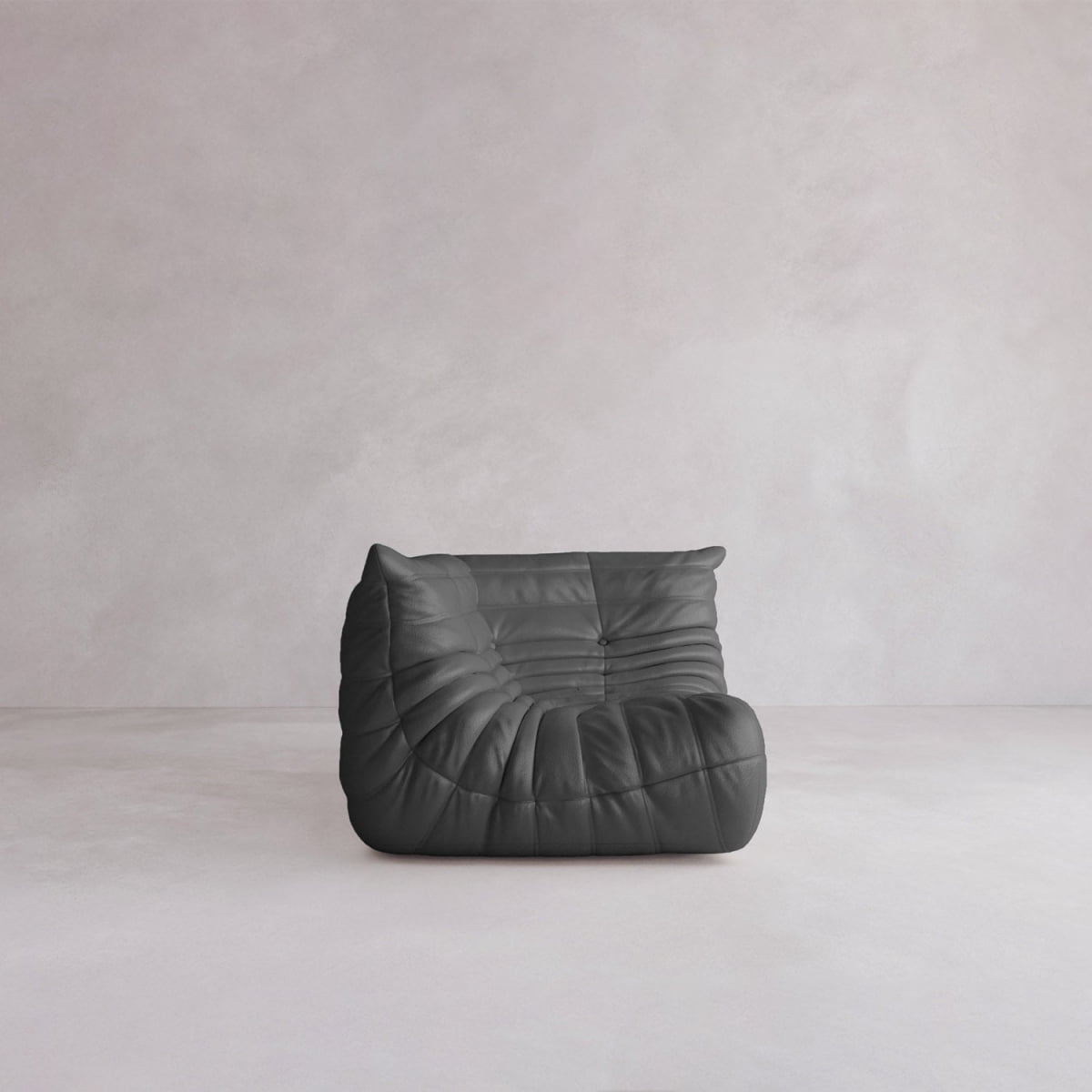 The Rolo Lounge Corner Sofa, a modern 70s-inspired piece, features sleek black leather and tufted cushions. It sits low on a minimalist floor against a pale, textured wall.