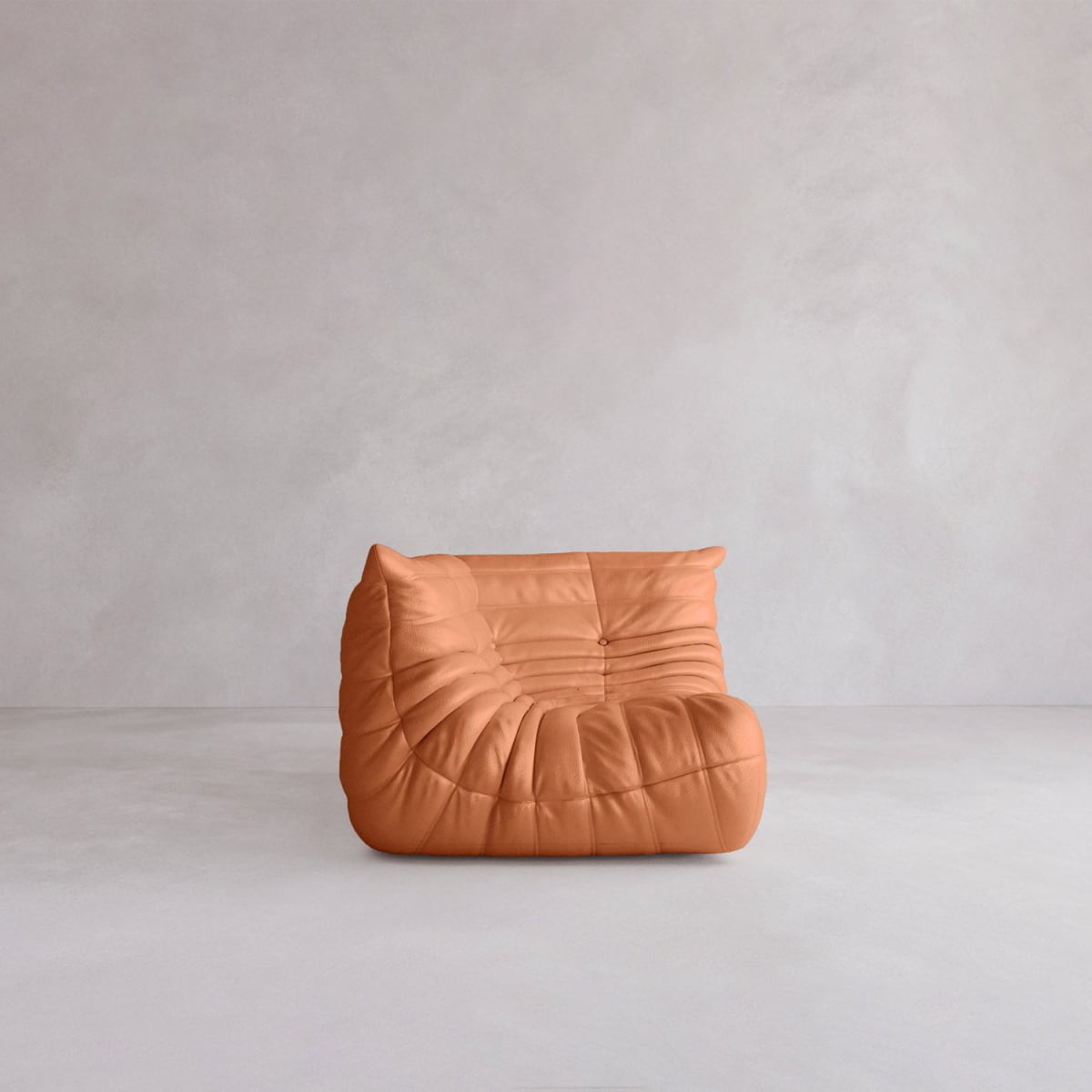A single Rolo Lounge Corner Sofa with 70s-inspired tan leather and a soft, wrinkled look sits on a smooth, light gray floor against a plain, light-colored wall.