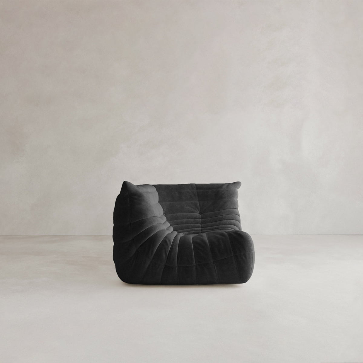 The Rolo Lounge Corner Sofa, featuring plush textured upholstery and a modern 70s-inspired design, sits armless and low on a minimalist floor against an off-white wall.