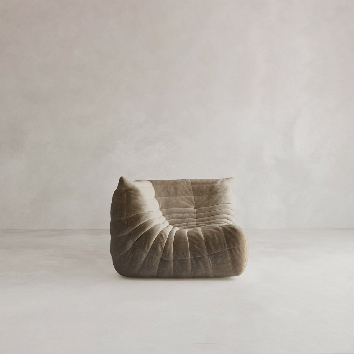 The Rolo Lounge Corner Sofa features a modern, armless design with low profile and soft, ruched brown upholstery, evoking a 70s-inspired style. It sits on a minimalist light floor against a pale textured wall for contemporary appeal.