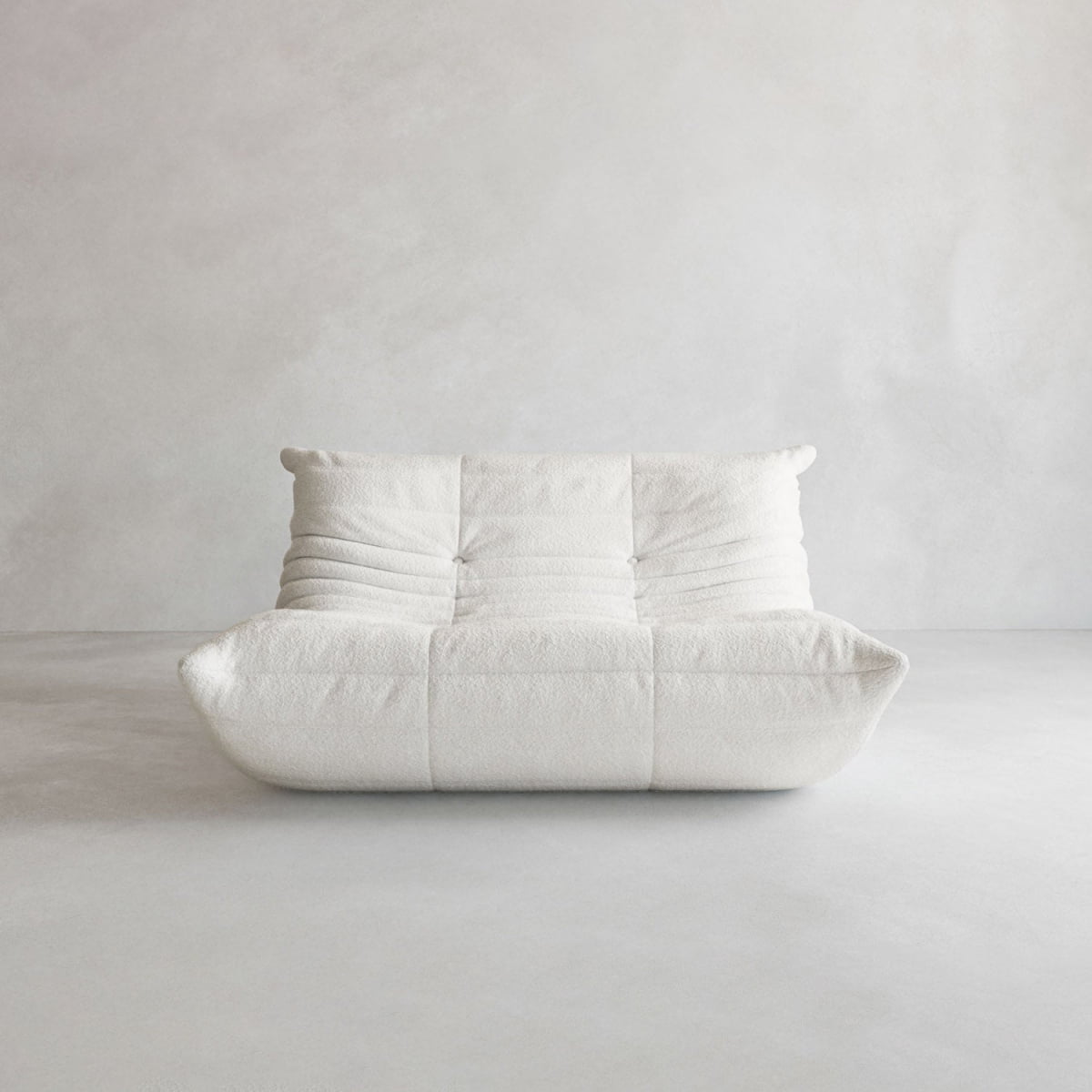 The Rolo Lounge Loveseat is a modern, white, cushioned sofa with a low profile and soft, rounded edges featuring subtle mid-century design influences, set against a plain light gray background.