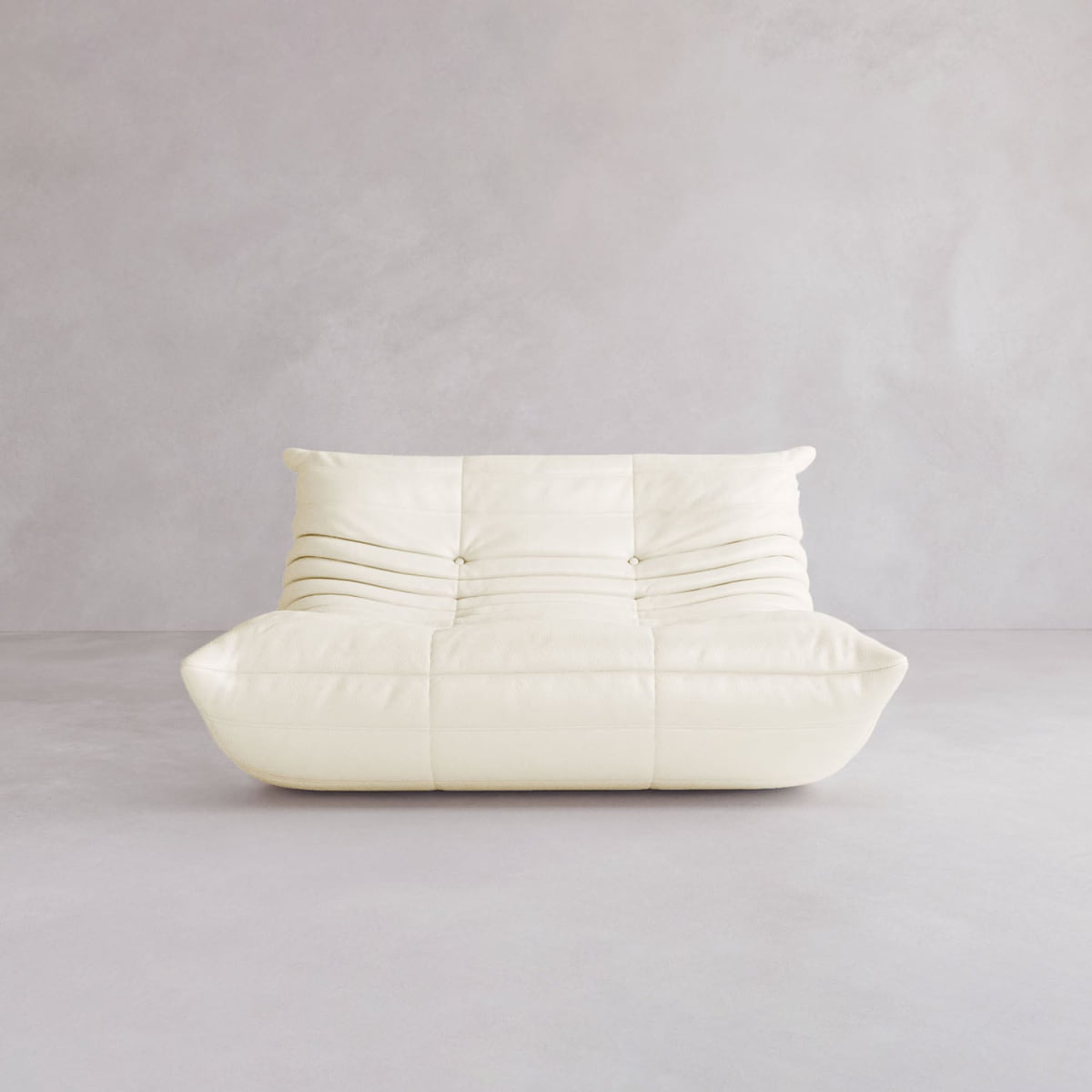 The Rolo Lounge Loveseat features a modern, low-profile white design with soft, tufted cushions and minimalist mid-century style, set against a light gray background.