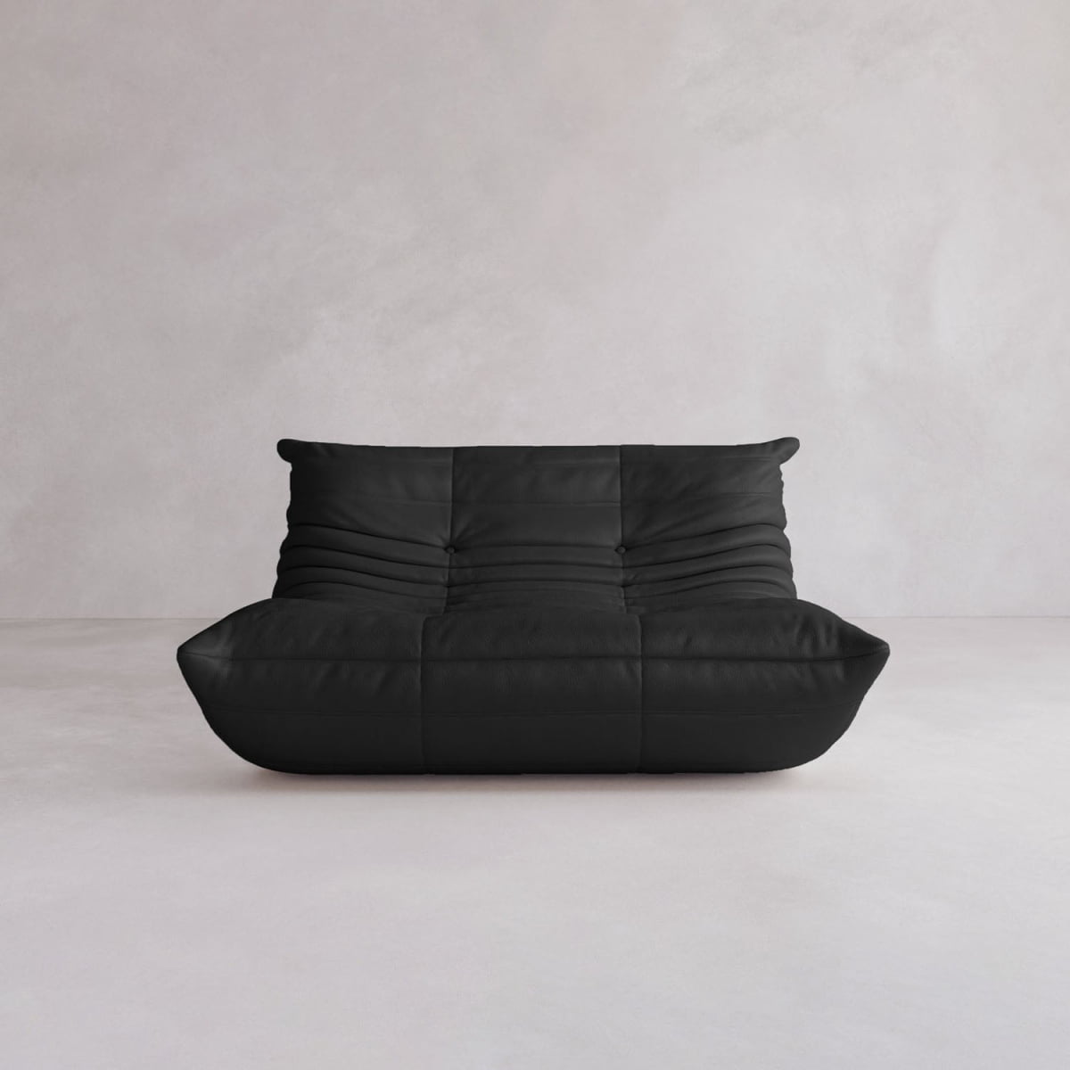 The Rolo Lounge Loveseat, featuring a modern black leather design with plush segmented cushions and subtle mid-century influences, sits against a plain light gray wall and floor.
