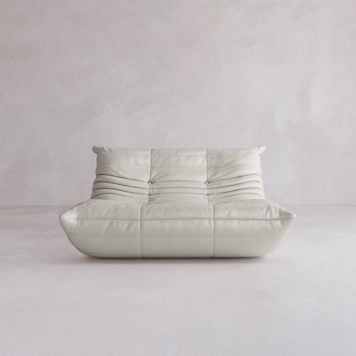 The Rolo Lounge Loveseat is a modern, low-profile white sofa with soft tufted cushions and a quilted design, inspired by mid-century style, displayed against a neutral light-colored background.