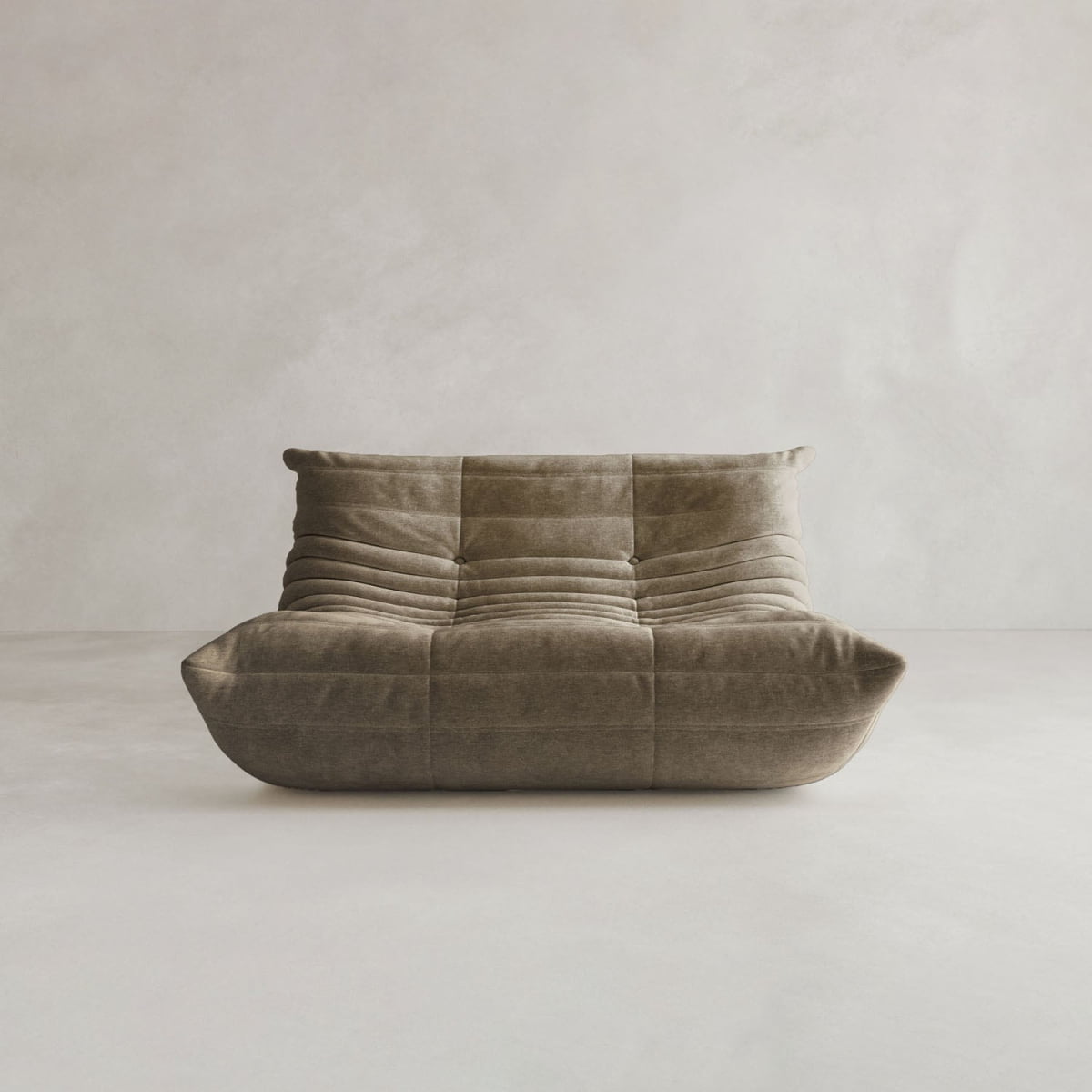 The Rolo Lounge Loveseat, a modern armless brown suede sofa with mid-century design, low profile, tufted cushions, and a slightly reclined back, sits in a minimalist room with light walls and floor.