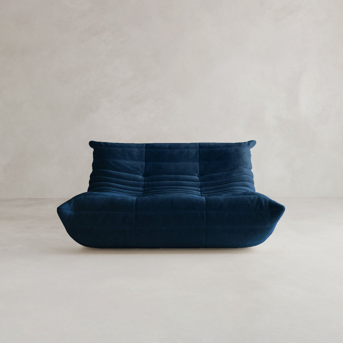The Rolo Lounge Loveseat is a modern, deep blue armless piece with a low profile and plush tufted upholstery, showcasing mid-century design elements. Its displayed against a plain light gray background.