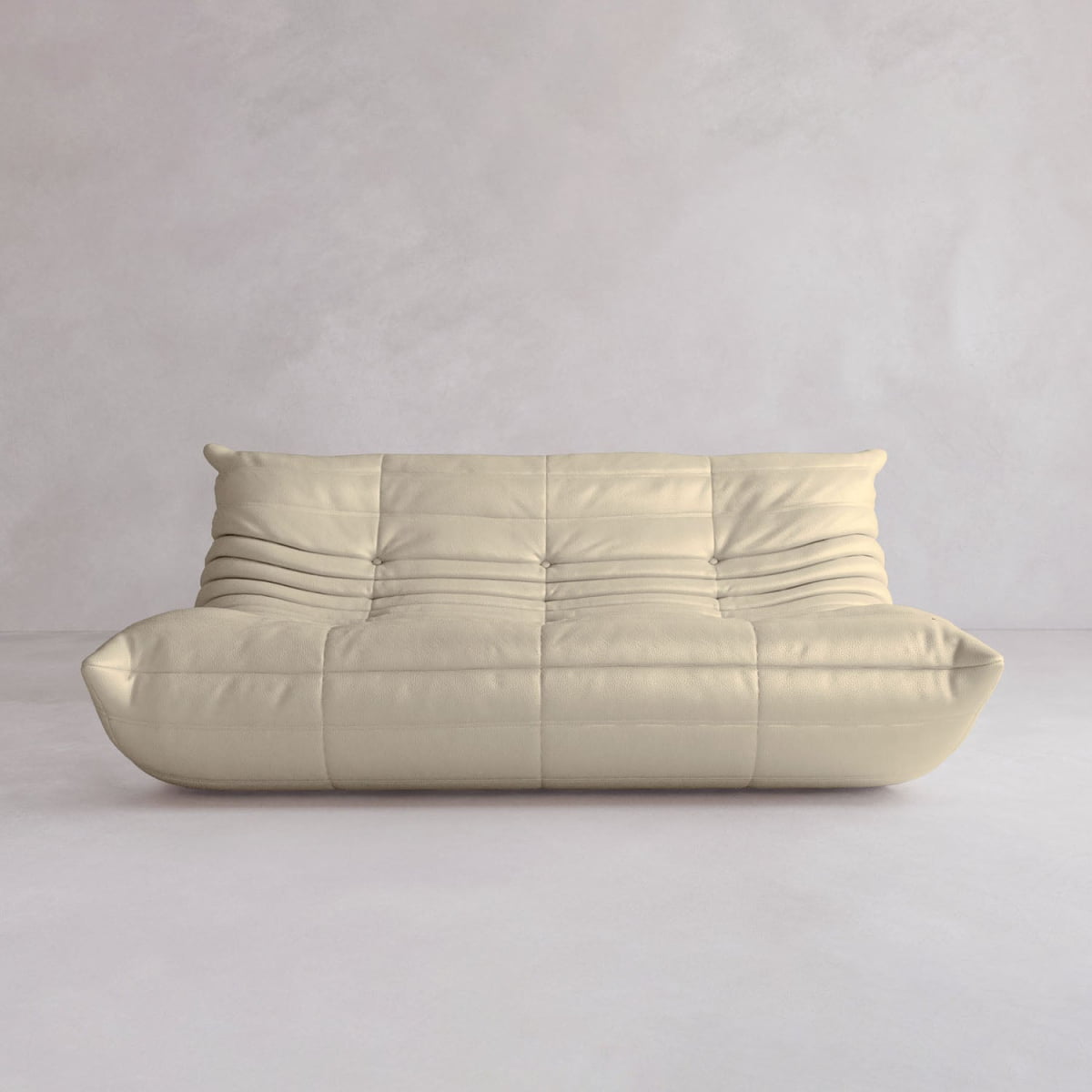 The Rolo Lounge Three Seater is a modern, minimalist beige sofa with soft cushions and subtle stitching, inspired by mid-century design, shown against a light gray textured wall in an empty room.