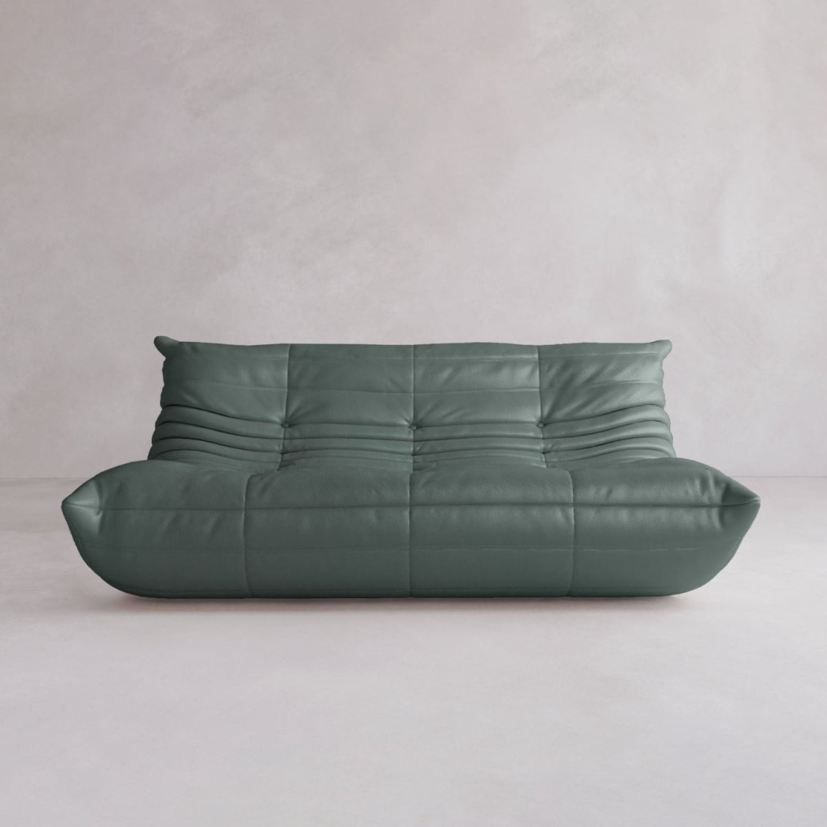 The Rolo Lounge Three Seater, a modern green leather sofa with deep tufting and mid-century inspiration, sits against a plain light-colored wall and floor.