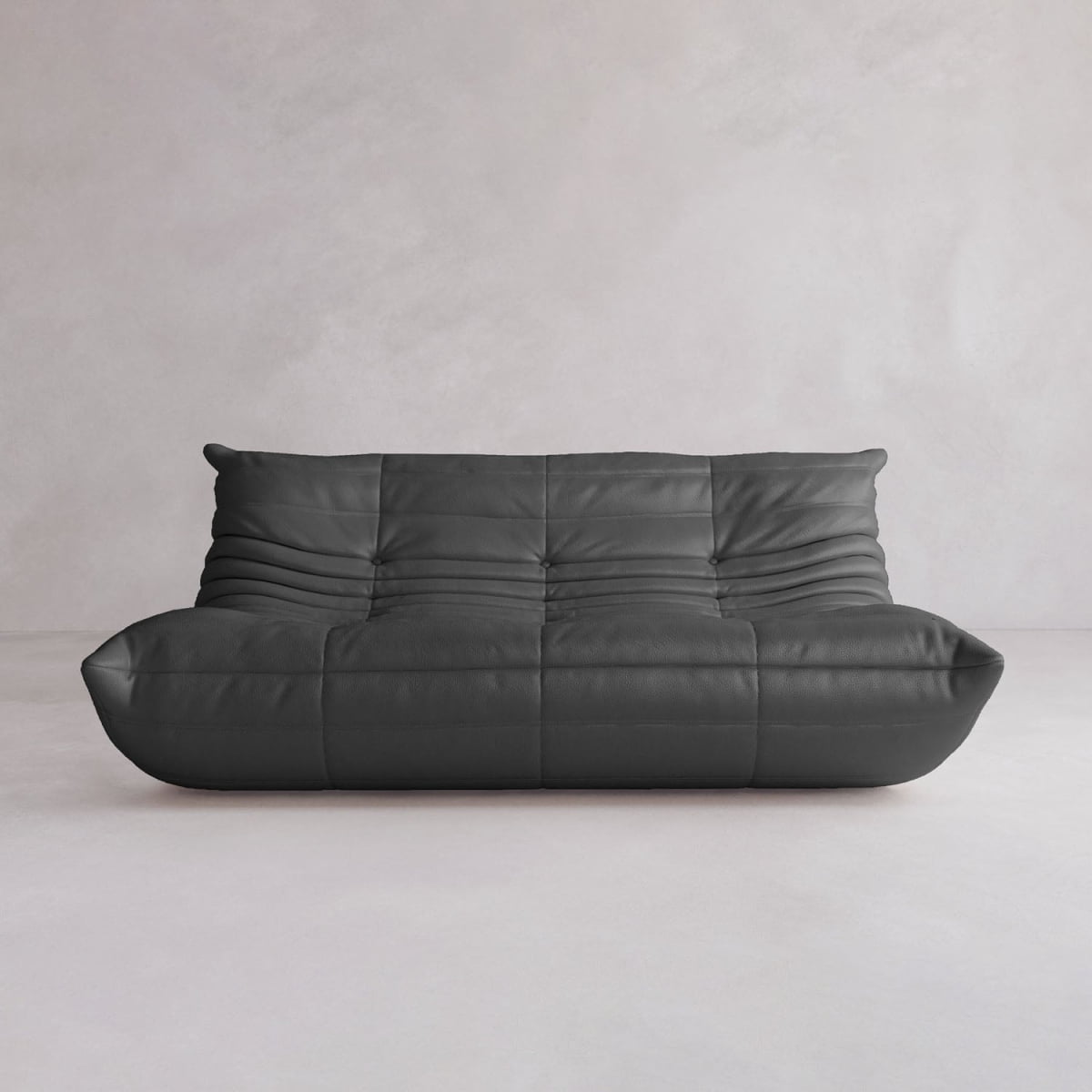 The Rolo Lounge Three Seater is a modern, low-profile black leather sofa with tufted cushions and mid-century inspired design, displayed against a plain light gray wall and floor.