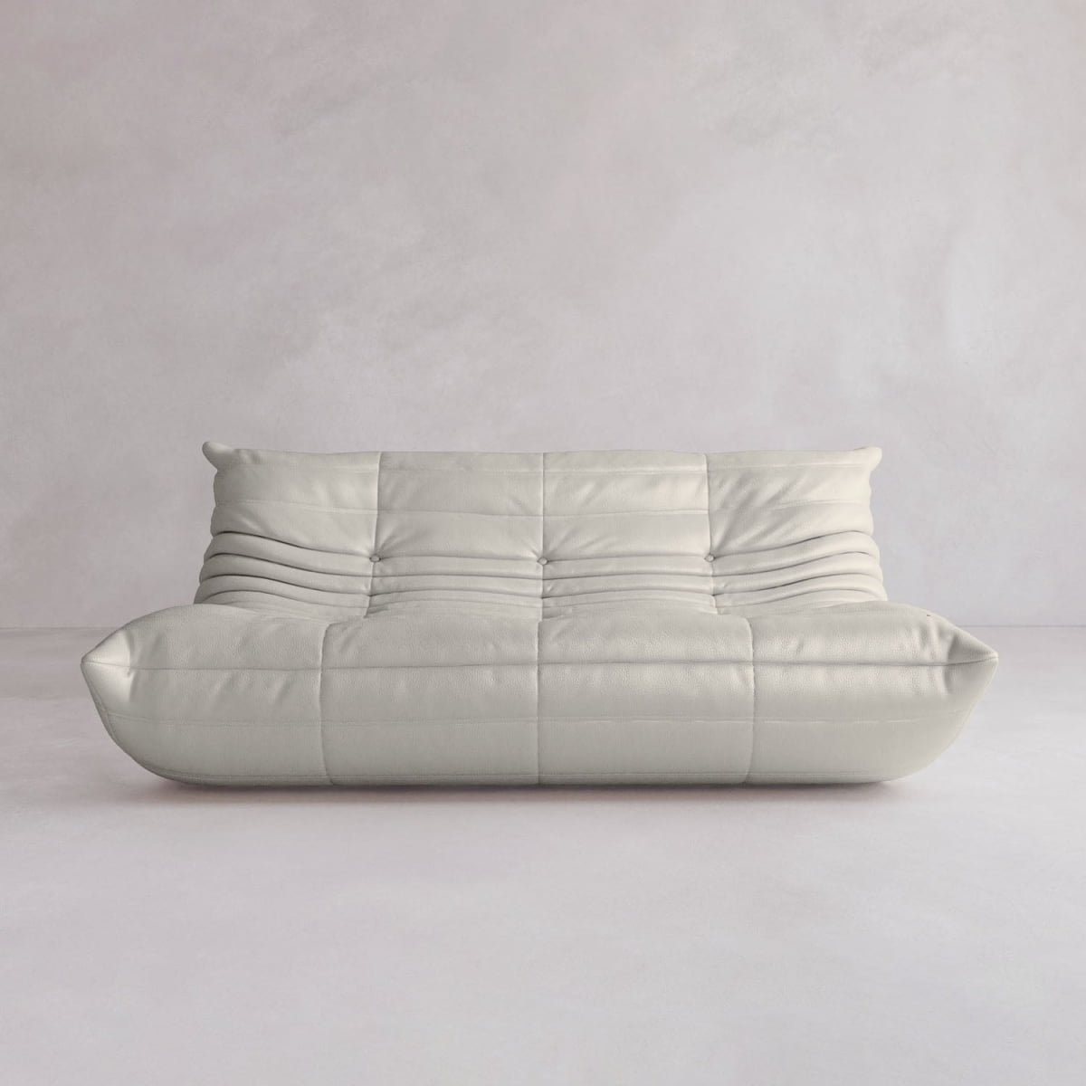The Rolo Lounge Three Seater is a modern, low-profile off-white sofa with soft, rounded edges and horizontal seams, adding mid-century flair to any space with plain light walls and floors.