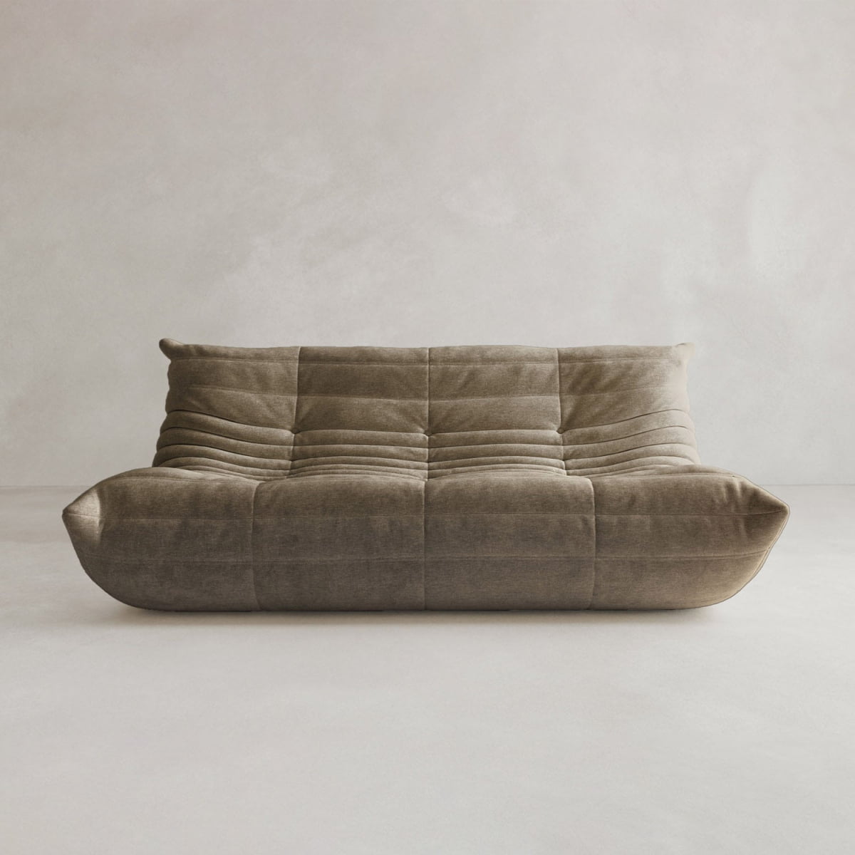 The Rolo Lounge Three Seater is a modern, low-profile brown sofa with plush tufting and soft curves, inspired by mid-century design, shown against a plain light background.