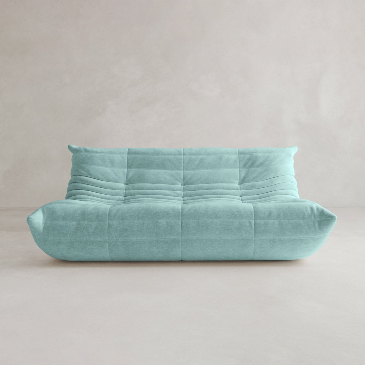 The Rolo Lounge Three Seater is a modern, turquoise, armless sofa with a plush quilted design and subtle mid-century influences, shown against a plain, light-colored wall and floor.