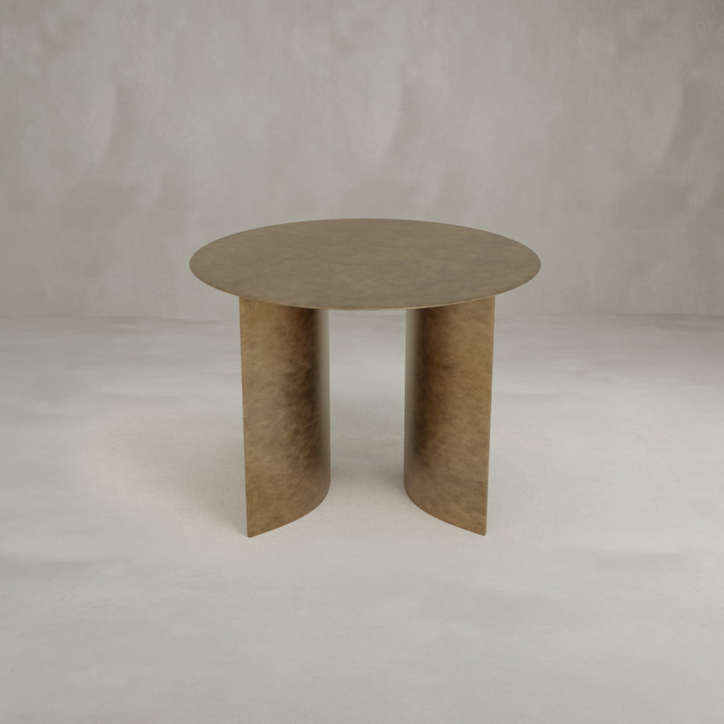 The Roma Coffee Table Short features a round, bronze-colored top and two wide, curved legs in a modern design, adding elegance to any space against a plain light gray background.
