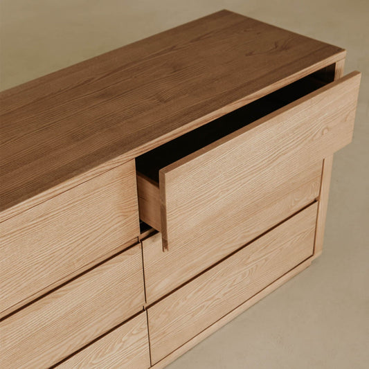 The Sandringham Dresser stands on a light floor with a partially open top drawer, highlighting its minimalist design, clean lines, and light wood grain—an ideal storage solution for modern bedroom decor.