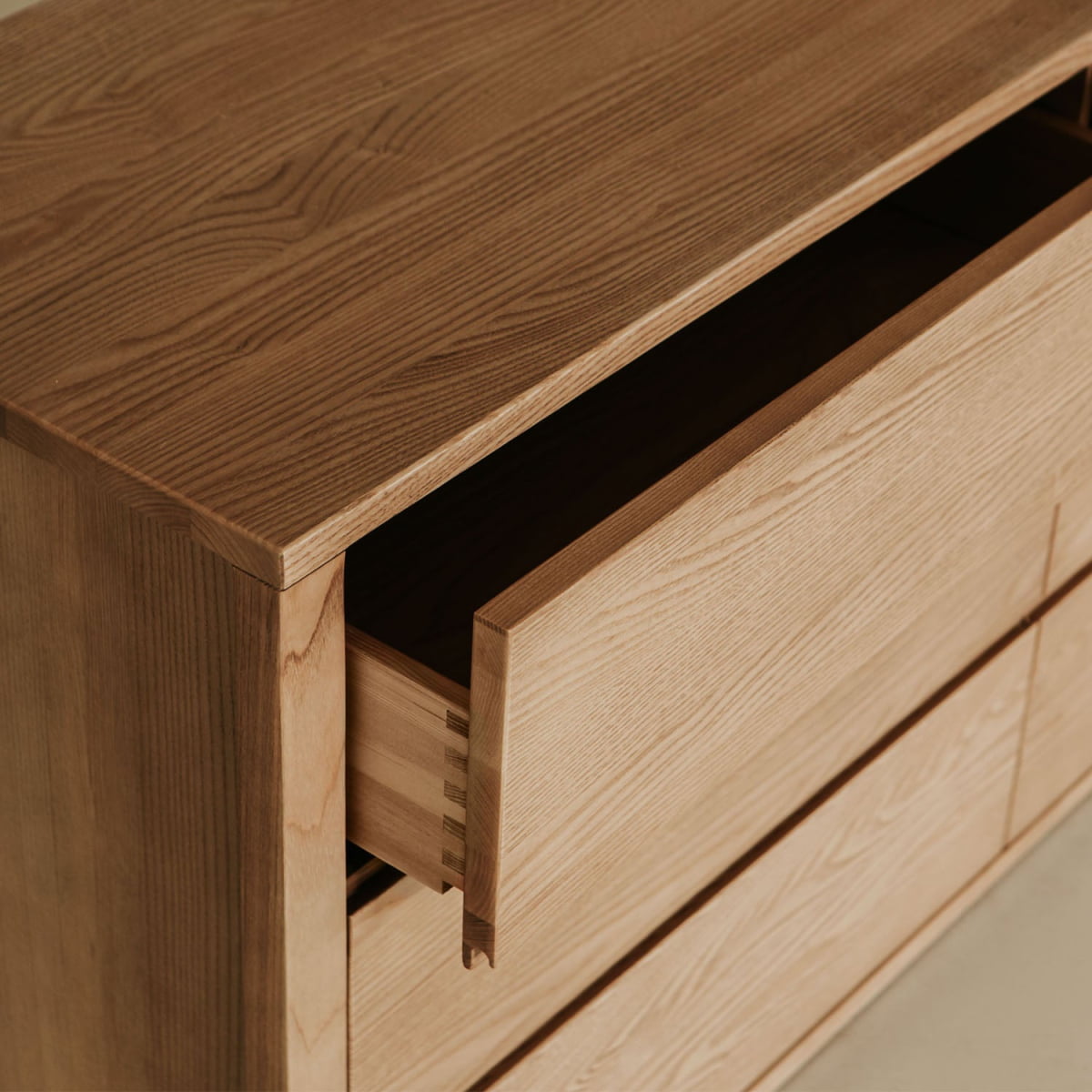 The Sandringham Dresser is shown in a close-up with its natural wood finish and one drawer partially open, highlighting dovetail joints—a stylish storage solution for any bedroom.