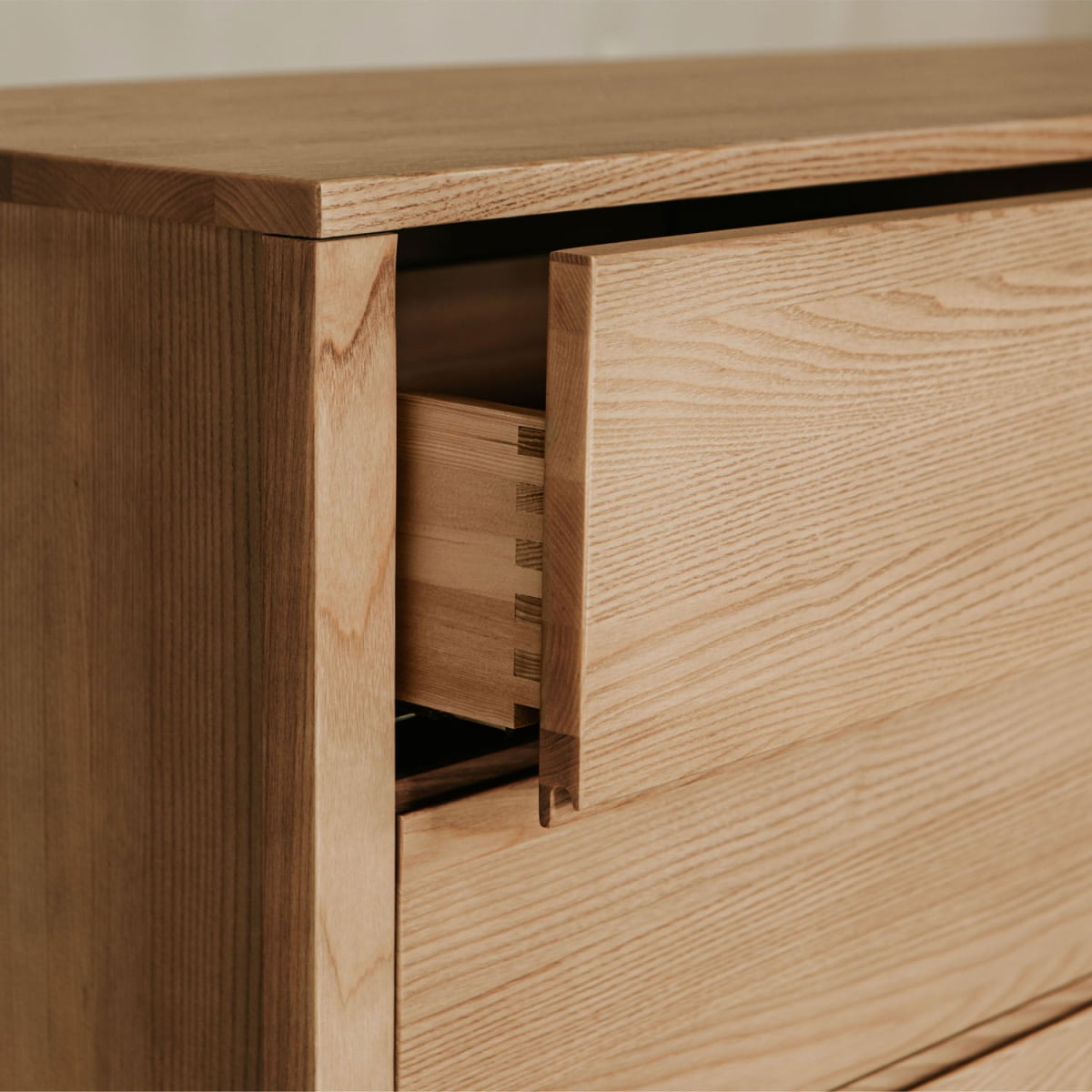 A close-up of the Sandringham Dresser in light wood with a partially open drawer showcases its elegant dovetail joint construction—an elevated detail for your bedroom decor and storage.