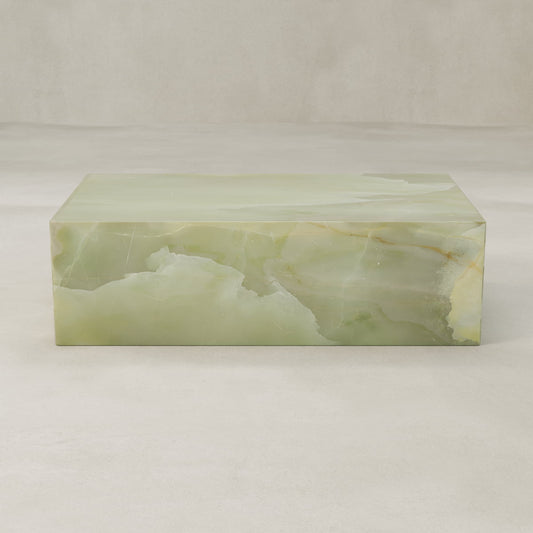 The Verdaine Onyx Coffee Table features a smooth, polished surface with natural color and veining variations, creating a serene statement against neutral, light backgrounds.