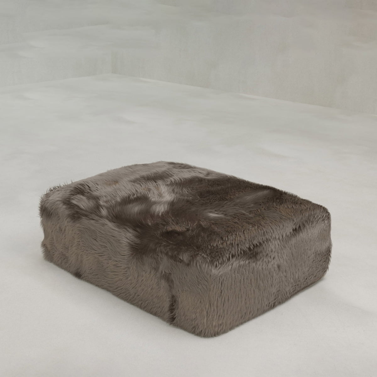 The Yeti Ottoman, a rectangular piece covered in plush faux fur, rests on a smooth light-colored floor in a minimalist room with pale gray walls, enhancing the look of the adjacent modular sofa.