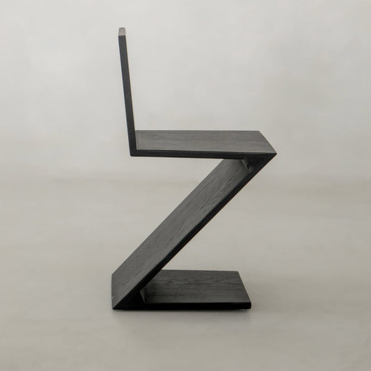 The Z Chair features a minimalist black design with modern, angular lines forming a bold zigzag silhouette, adding sophisticated style to contemporary interiors when set against a light background.